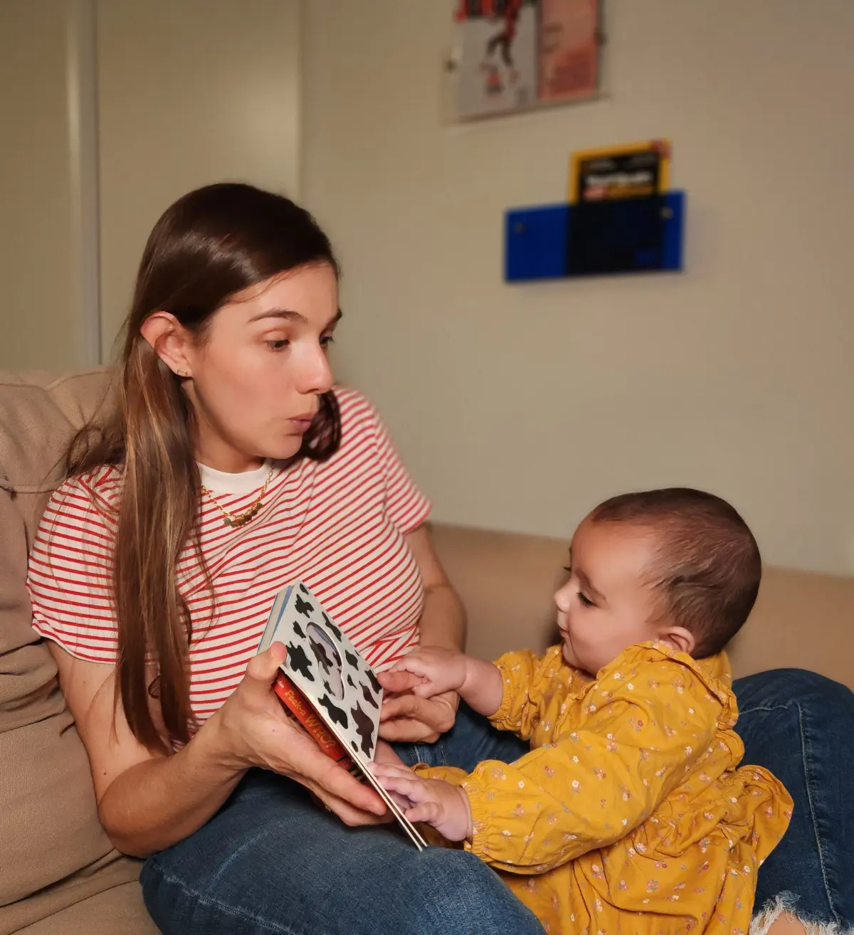 Mamá cantando y leyendo con su bebé en el sofá
